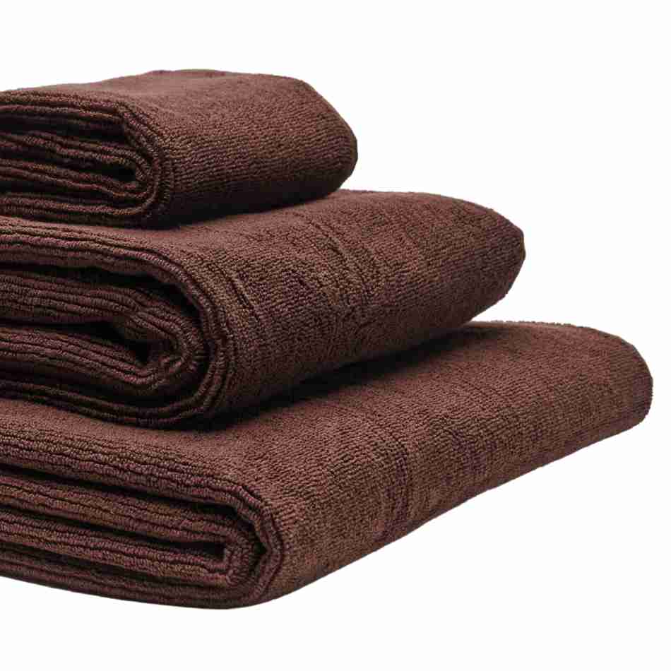 Tre håndklæder i økologisk bomuld og af forskellig størrelser stablet oven på hinanden. Farven på håndklæderne er brun.