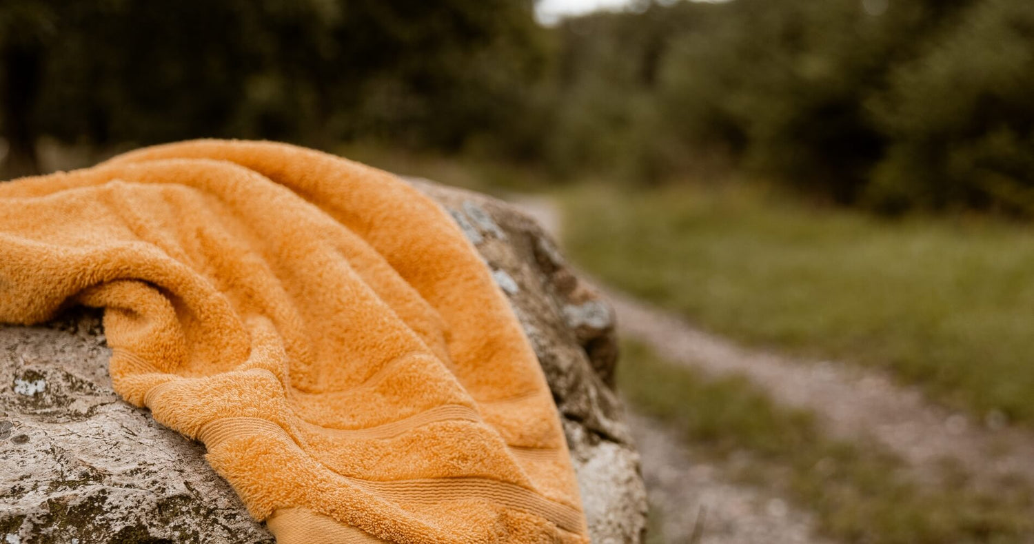 Orange håndklæde liggende på en stor sten i naturlige omgivelser