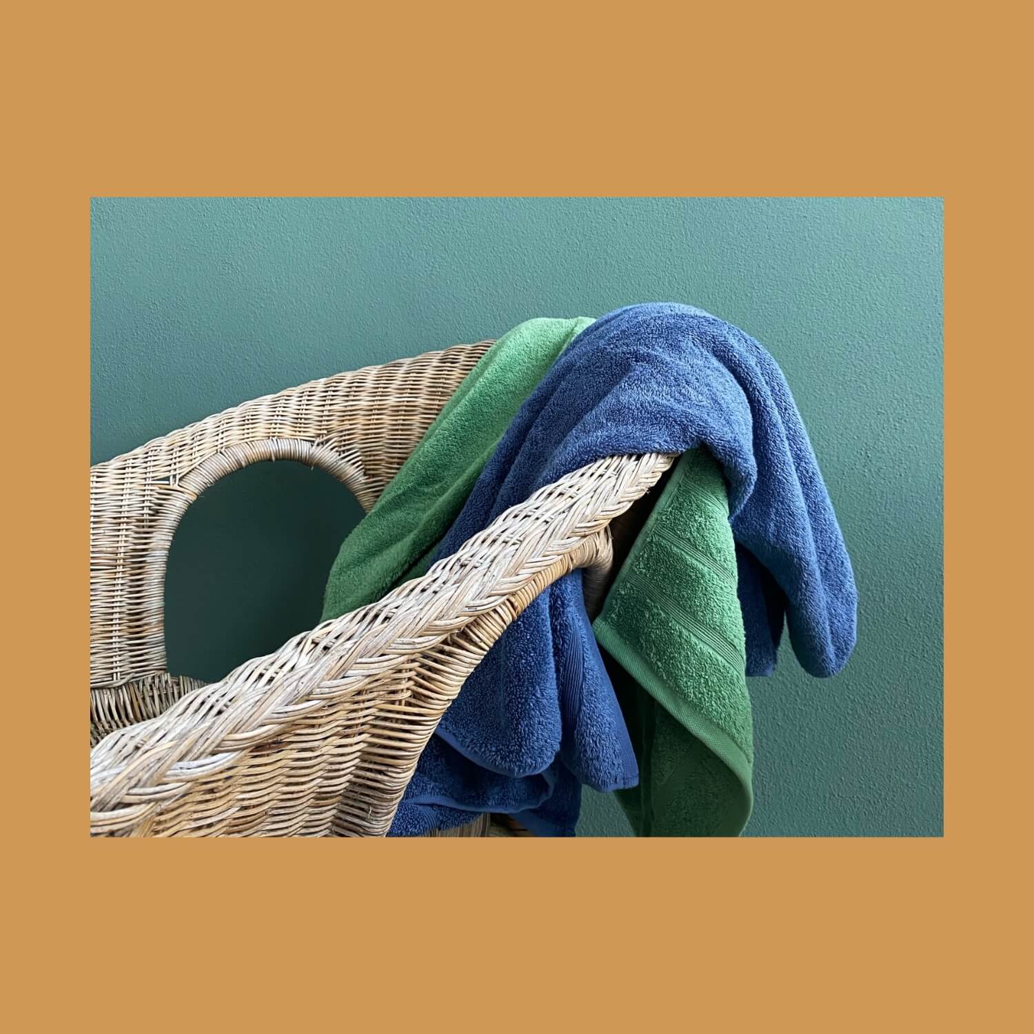 To håndklæder kastet henover en stol. Farverne på håndklæderne er grøn og mørkeblå