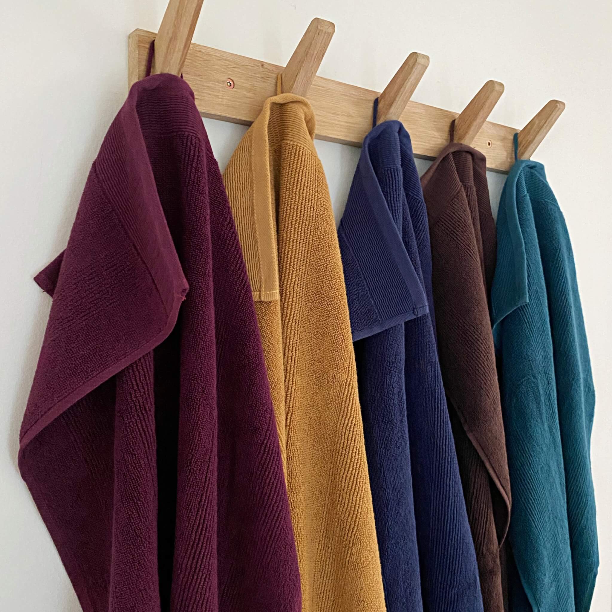 Håndklæder i forskellige farver hænger på en knagerække i entréen