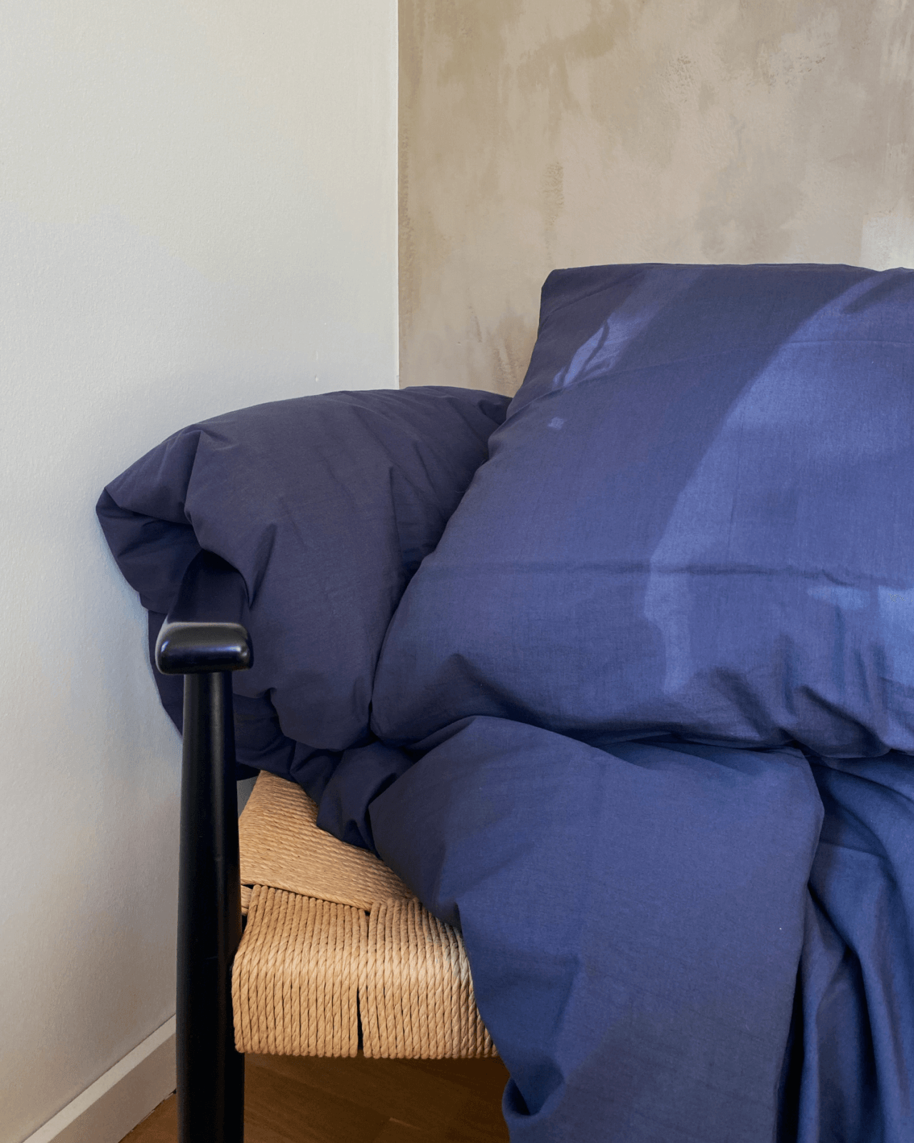 Blåt sengetøj liggende på en stol foran en beige og hvid væg