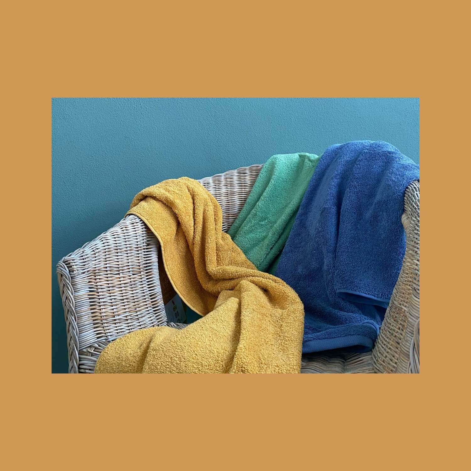 Håndklæder kastet hen over en stol. Farverne er karrygul, græsgrøn og gråblå.