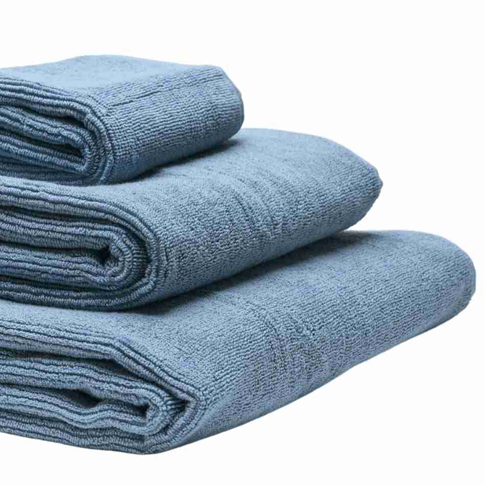 Tre håndklæder i økologisk bomuld og af forskellig størrelser stablet oven på hinanden. Farven på håndklæderne er blå.