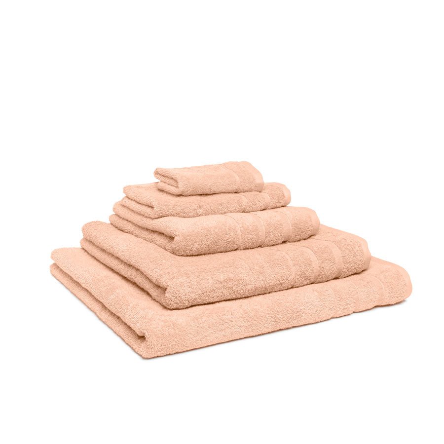 Fem håndklæder i økologisk bomuld og af forskellig størrelser stablet oven på hinanden. Farven på håndklæderne er melon.